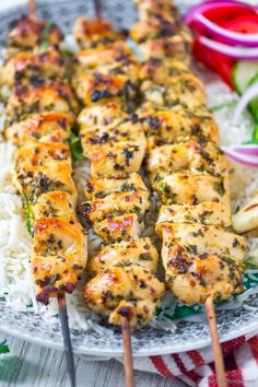 chicken kabobs on skewers with white rice and red onion garnish