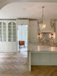 a large kitchen with marble counter tops and white cabinets