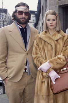 three people standing next to each other in front of a building wearing fur coats and hats