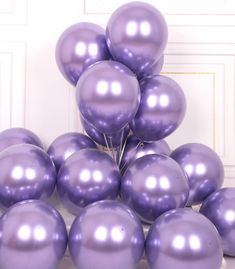 a bunch of purple balloons sitting on top of a white table next to a door