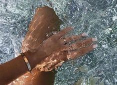 a person's hand in the water with rings on their wrist and two other hands