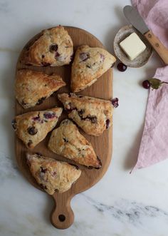 blueberry scones on a cutting board with butter and cranberries in the background