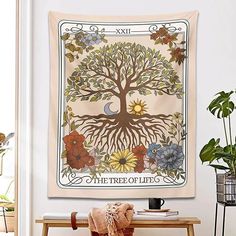 the tree of life tapestry is hanging in front of a table with a potted plant on it