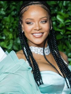 a woman in a blue dress with braids on her head and smiling at the camera