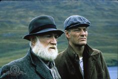 two men with white hair and beards standing next to each other in the mountains