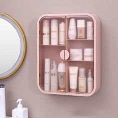 a pink bathroom cabinet with many bottles and soaps on the shelves next to a mirror