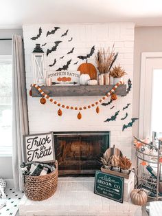 a living room decorated for halloween with pumpkins and bats on the fireplace mantel