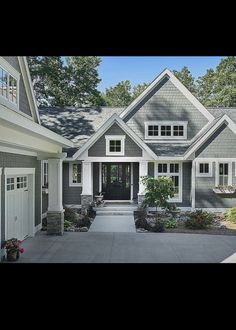 a large gray house with white trim on the front door and windows, along with two car garages