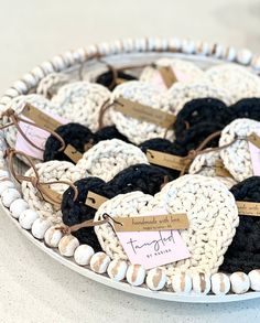 there are many crocheted hearts with tags on them in a bowl that is sitting on the table