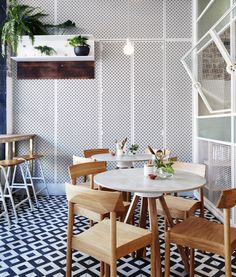 a table and chairs in a room with patterned floor tiles on the walls, potted plants hanging from the ceiling