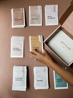 a person holding a box with several different types of flower seeds in it on a table