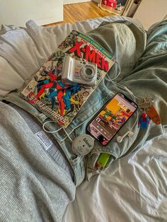 an open book, camera and cell phone laying on top of a bed