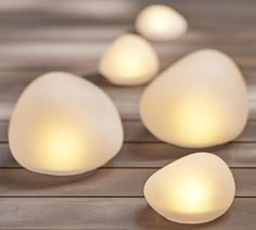 three white eggs sitting next to each other on a wooden table with lights in them