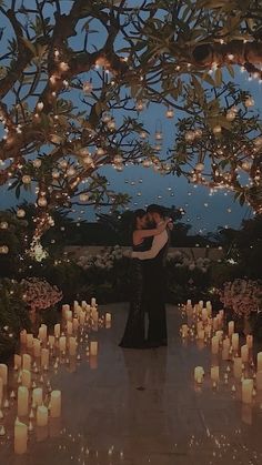 a man and woman standing under a tree filled with candles