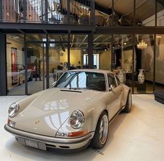 a car is parked in the middle of a room with glass walls and large windows