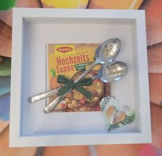 spoons are sitting in a shadow box with some food on it and a bag of hoochfets