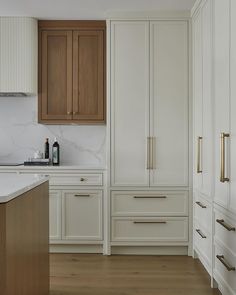 a kitchen with white cabinets and wood floors