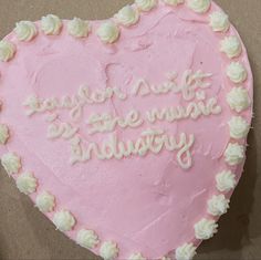 a pink heart shaped cake with white frosting and writing on the side that says taylor dirt is the music industry