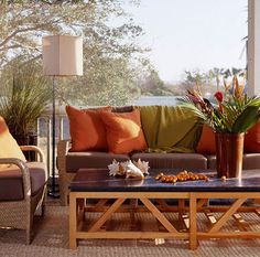 a living room filled with lots of furniture next to a large glass window covered in plants