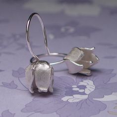 These Lily of the Valley inspired earrings are perfect for any occasion. Their unique texture makes each pair one of a kind.  935 argentium sterling silver  Ear wire: 2cm from top of flower to top of wire Flower: 10mm x 10mm Handmade Silver Earrings For Bridesmaid Gift, Silver Flower Shaped Hoop Earrings For Wedding, Delicate Sterling Silver Earrings For Bridesmaids, Delicate Silver Earrings For Bridesmaid Gift, Sterling Silver Single Flower Earring For Weddings, Silver Flower Drop Earrings For Bridesmaid Gift, Silver Lever Back Earrings For Wedding, Silver Wedding Earrings With Lever Back, Wire Flowers