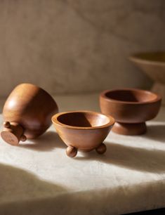 three small wooden bowls sitting on top of a table next to a bowl and spoon