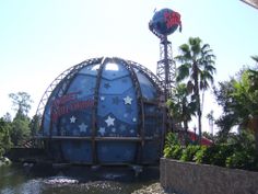 a large blue ball sitting on top of a river next to a tall water tower