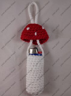 a crocheted red and white mushroom hanging from a hook with a can in it