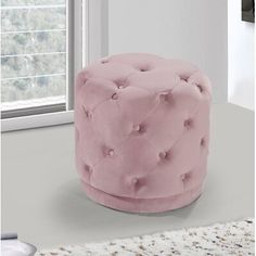 a pink ottoman sitting in front of a window