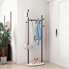 a coat rack with several pairs of shoes hanging from it's sides, next to a potted plant