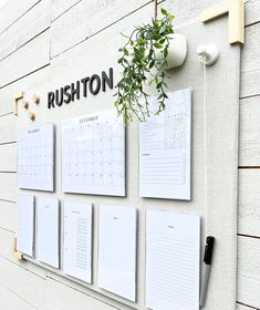 a white wall with calendars on it and a plant growing out of the top