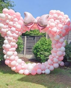 a heart shaped balloon arch in the shape of a bow with pink and white balloons