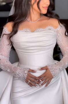 a woman in a white wedding dress with her hands on her hips and wearing a tiara