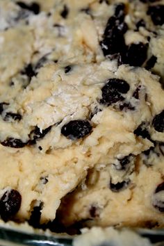 a close up of a cookie dough in a glass bowl with raisins on it