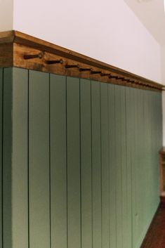 there is a wooden shelf on the wall in this room with green paint and wood paneling