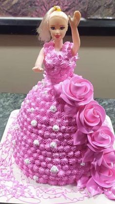 a barbie doll cake with pink flowers on it's bottom and one hand in the air