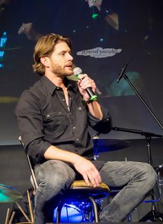 a man sitting in a chair while holding a microphone