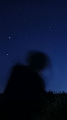 the silhouette of a person standing in front of a night sky