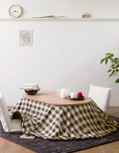 the table is covered with a black and white checkerboard tablecloth, which sits on an area rug next to a potted plant