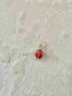 a red and silver charm sitting on top of a white carpeted floor next to a pair of scissors