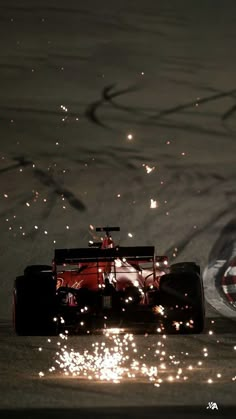 a red race car driving down a track with sparks coming out of the front wheel