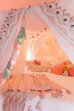 a bed with white sheets and pink pillows in a room that has lights on the ceiling