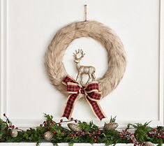 a christmas wreath with a deer decoration hanging from it's side on a mantel