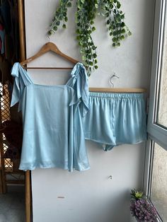 These days, more brides are moving away from traditional robe options for getting ready and are looking for unique gifts like pjs for their bridesmaids. Style We have several different styles of Pj sets available. The photo you see above is of Tie Ribbon Tank Top style Pj set.  We have made these pyjama sets in long and short version. The longer ones can go with the comfy, peaceful vibe and many mother of the bride/groom also prefer it. If you want sexier or more chic look, you go for the shorts. In the pictures, you can see both the versions to get a better idea. Fabric Colors Our exclusive bridesmaid pjs come in 35 different colors, but if you have a specific wedding color in mind that you'd like us to match, we'd be more than happy to do so. Our color range spans from classic tones like Summer Wedding Satin Sleepwear, Blue Satin Sets For Summer, Satin Pjs, Bridesmaid Pjs, Girls Pjs, Tie Ribbon, Short Pj Set, Sleep Shorts, Tie Knots