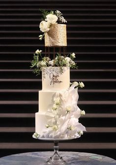 a three tiered wedding cake with white flowers and greenery