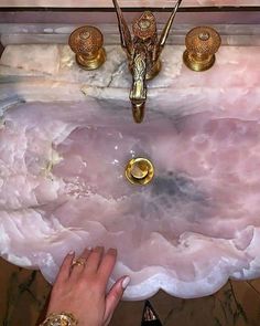 a person's hand is reaching into a sink that has pink marble on it