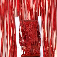 a red piece of paper sitting on top of a white chair in front of curtains