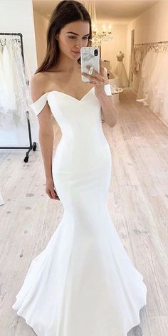 a woman is taking a selfie in her wedding dress while wearing a white gown