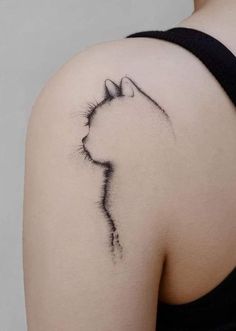 a cat tattoo on the back of a woman's shoulder