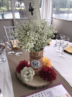 a vase with flowers is sitting on a table near wine glasses and menus in front of a window