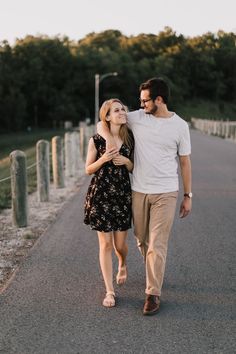 a man and woman walking down the street holding each other's hand as they look into the distance